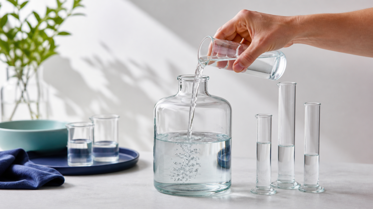 Clear liquid being poured among one-liter and smaller graduated glass vessels
